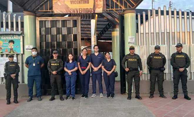 Auxiliares de polic&iacute;a y personal de salud frente a la fachada de una instituci&oacute;n educativa