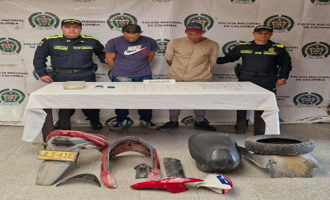 Dos policias con un hombre capturado en el medio, y partes de motocicletas en el suelo