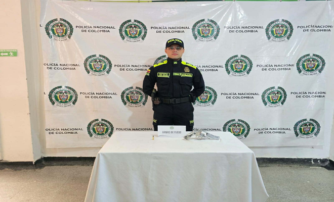 Polic&iacute;a detr&aacute;s de una mesa con un rev&oacute;lver incautado. 