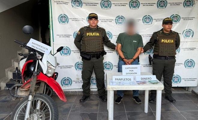 Dos policías con un capturado y una motocicleta