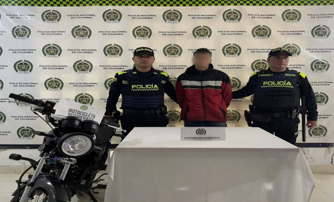 Dos policias con un hombre capturado en el medio y al lado izquierda de la foto una moto de color negro