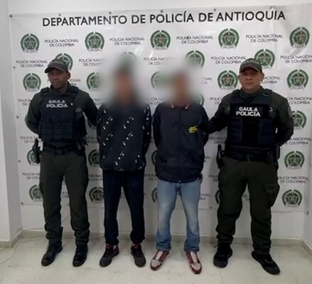 Dos policías del GAULA custodian a dos capturados por extorsión