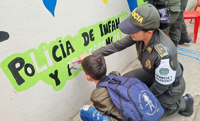 Mujer polic&iacute;a con un ni&ntilde;o pintando un mural