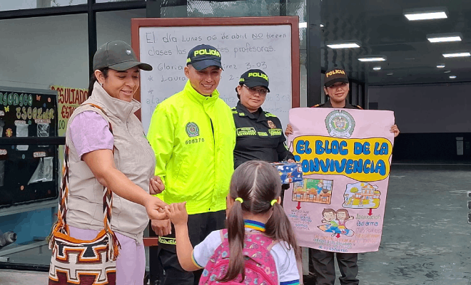 Una persona del ICBF tres polic&iacute;a sosteniendo una cartelera y una ni&ntilde;a con uniforme