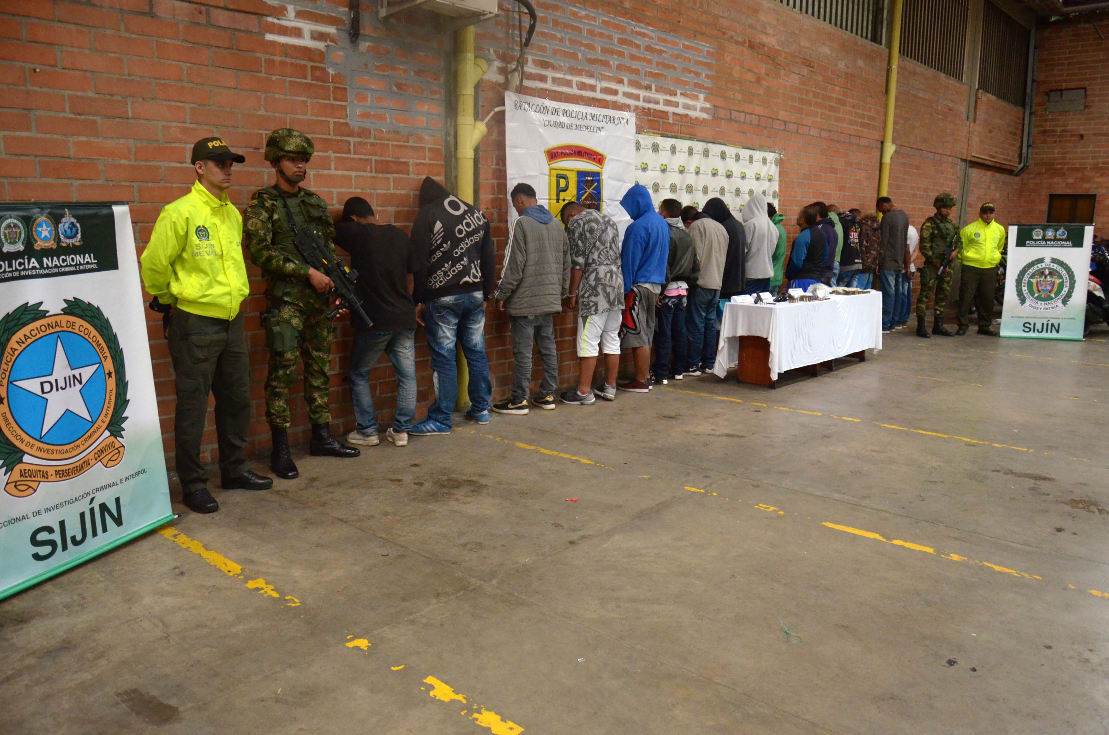 Policías de la SIJIN y militares custodian a capturados con esposas y elementos