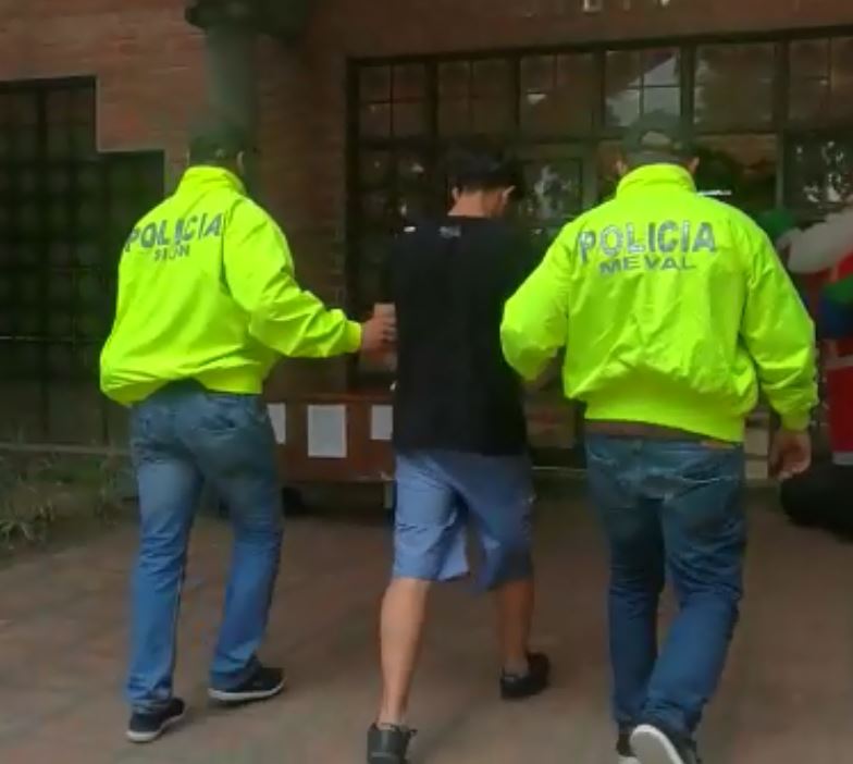 Dos policías- Sijin-caminando llevan de los brazos a una hombre capturado