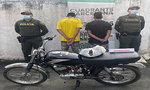Dos personas capturadas- policías custodiando-marihuana incautada