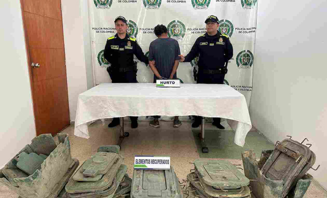 Hombre capturado en medio de dos policías, en frente elementos incautados