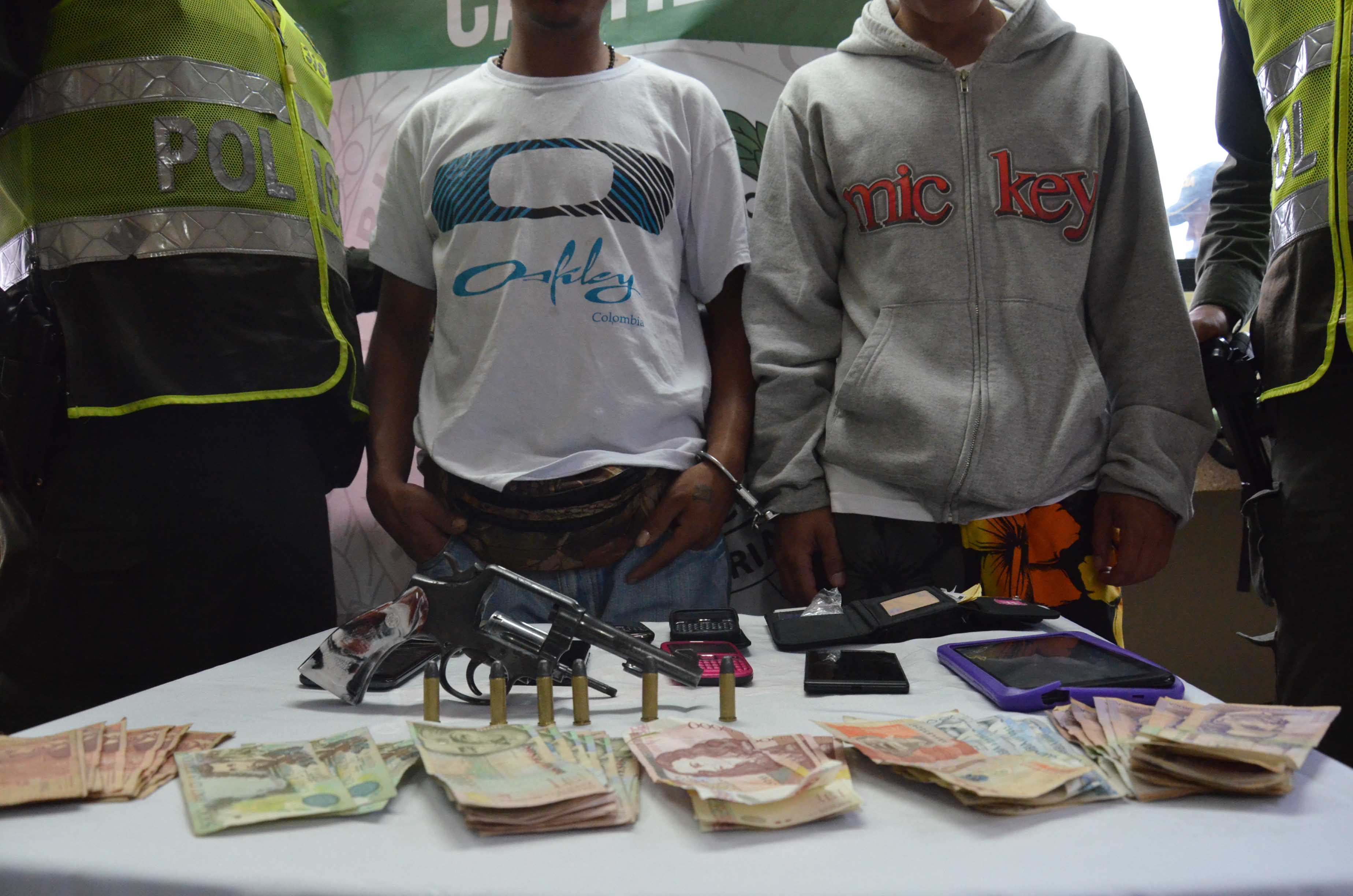 Dos hombres custodiados por policias luegode ser capturados por hurto en Medellín 