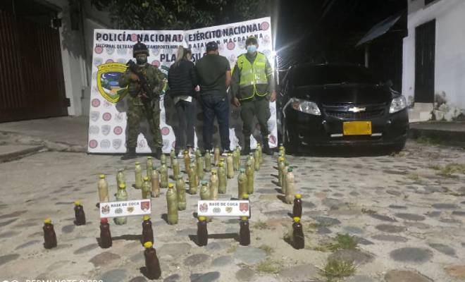 2 personas capturadas-policías custodiando-base de coca incautada-vehículo inmovilizado