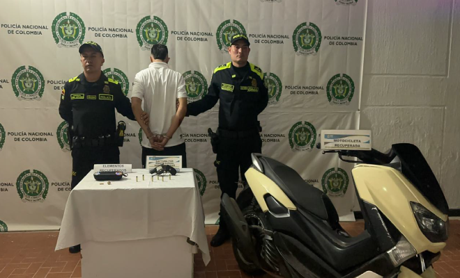 Hombre capturado en medio de dos polic&iacute;as, en frente elementos incautados