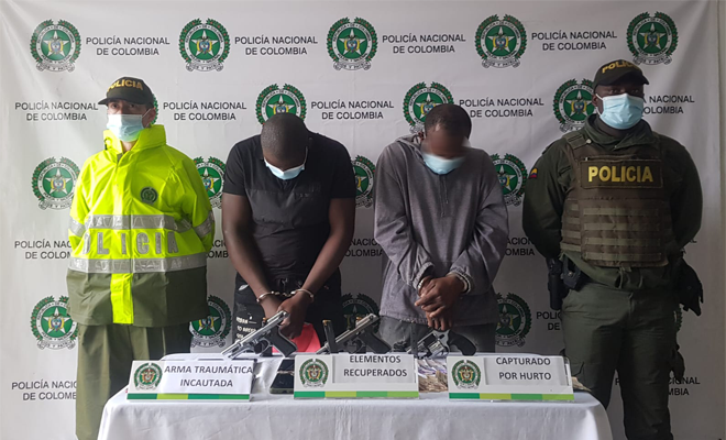 personas capturadas-policías custodiando-armas de fuego incautadas