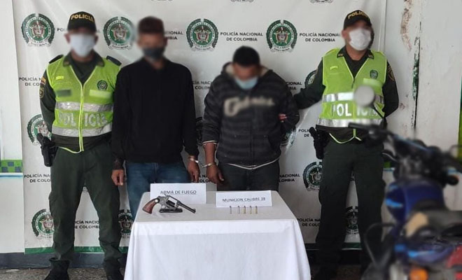 2 personas capturadas-policías custodiando-arma de fuego y munición incautada