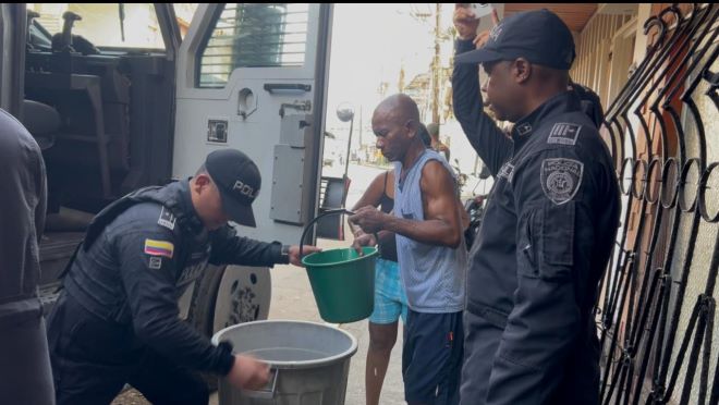 dos policías al lado de un ciudadano brindándoles agua