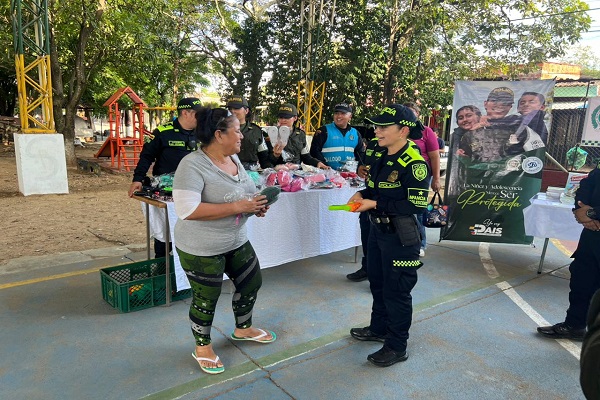 Una Policía con una ciudadana y cuatro policías detrás listos para iniciar con la actividad Cambiemos Juguetes por Vidas
