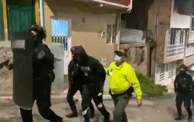 Polic&iacute;as trasladando a uno de los capturados por una de las calles de la localidad de Usme