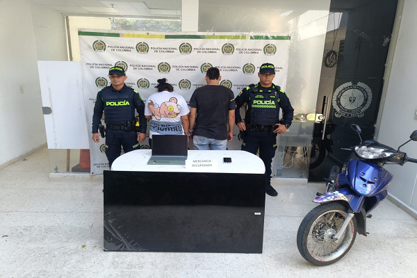 Dos Policías con dos personas capturadas y una motocicleta 