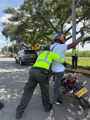 un policía realizando registro aun hombre en una motocicleta 